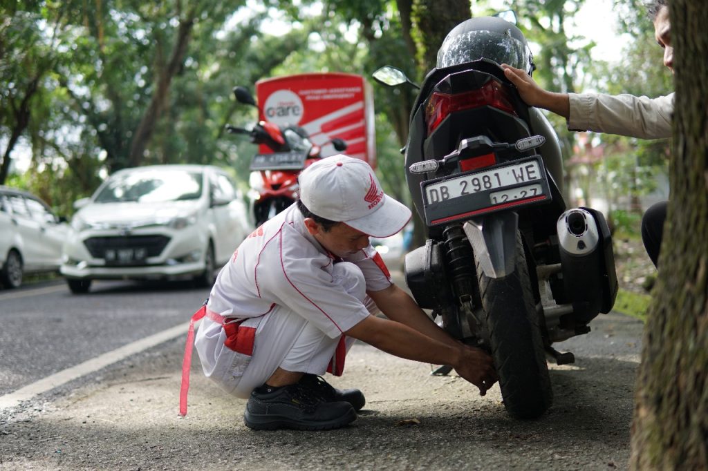 Tehnisi Honda Care sedang memperbaiki sepeda motor yg rusak
